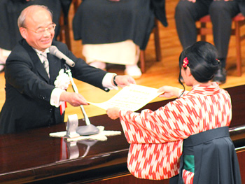 講堂での式典　学科総代が光田学長（人間関係学科所属）から学位記を授与される