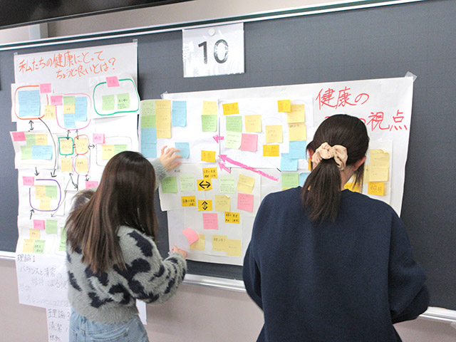 看護学部 基礎ゼミⅡ 3学科協同学習による成果物を、発表のために掲示している場面です