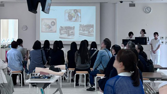 学生からの説明に真剣に見ている来校者たち